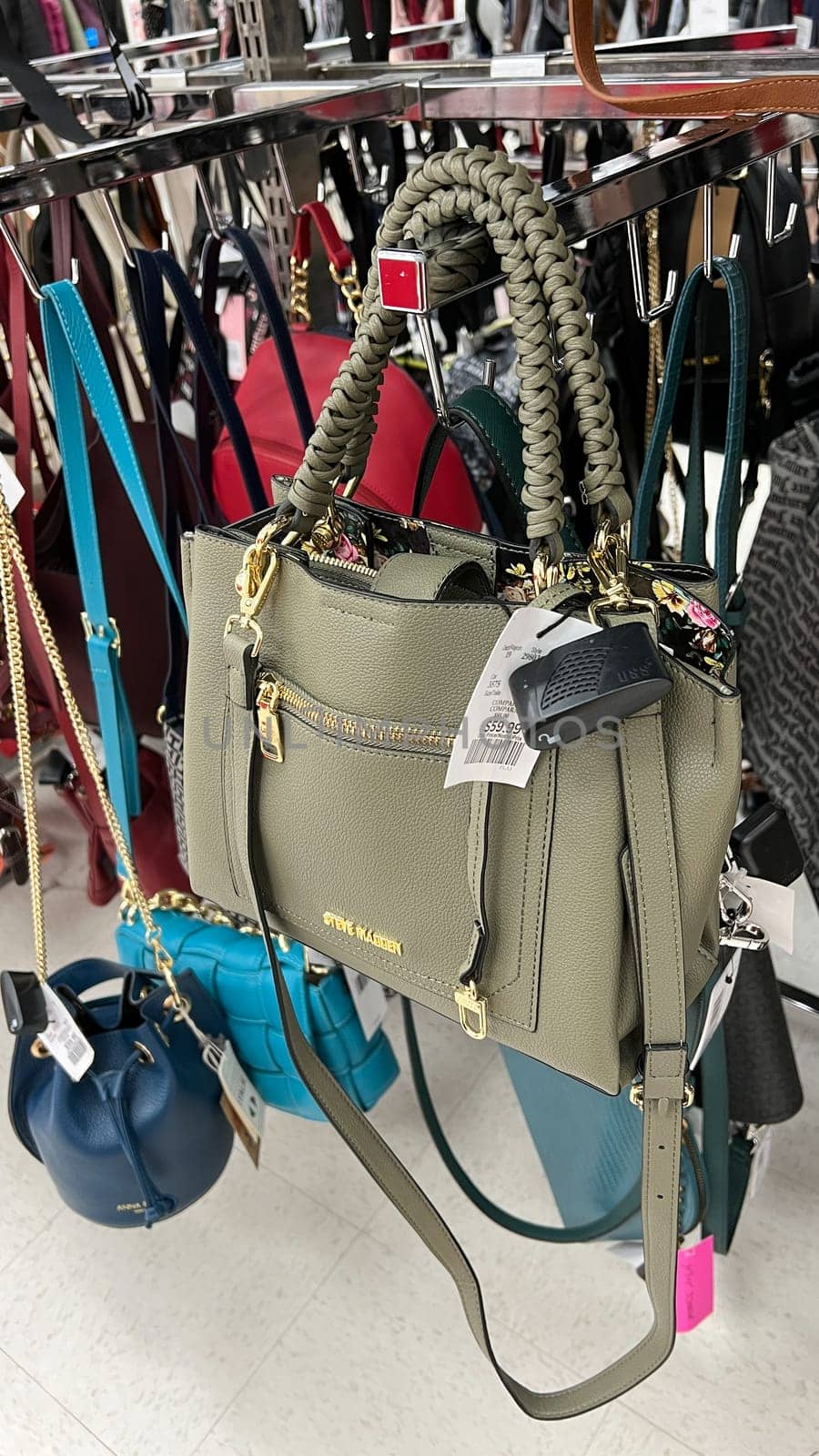Ottawa, ON Canada - May 01, 2025: Stylish green handbag with braided handles displayed on a rack in a retail store, showcasing modern design and luxury accessories for fashion enthusiasts and shoppers.