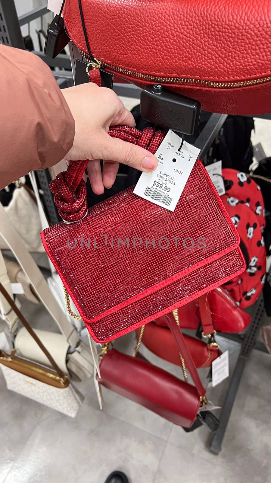 Ottawa, ON Canada - May 01, 2025: Stylish red handbag rhinestones with handles displayed in a retail store, showcasing modern design and luxury accessories for fashion enthusiasts and shoppers.