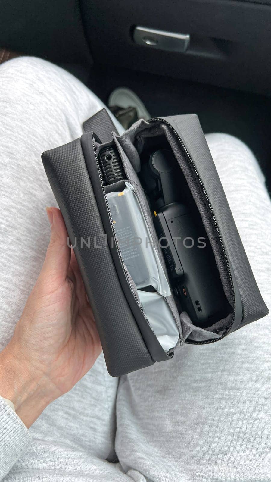 Ottawa, Canada - April 05, 2025: A hand grips a DJI Osmo Pocket 3 camera, resting on a lap with a sleek black carrying case, highlighting innovative design for capturing steady videos
