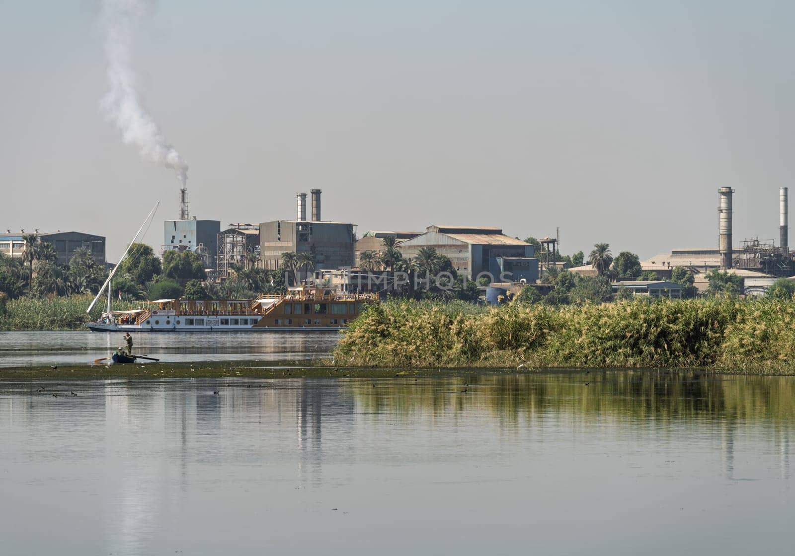 Edfu,. Egypt - 6 November 2024: Edfu steel factory, including industrial buildings, smokestacks, seen from the Nile River