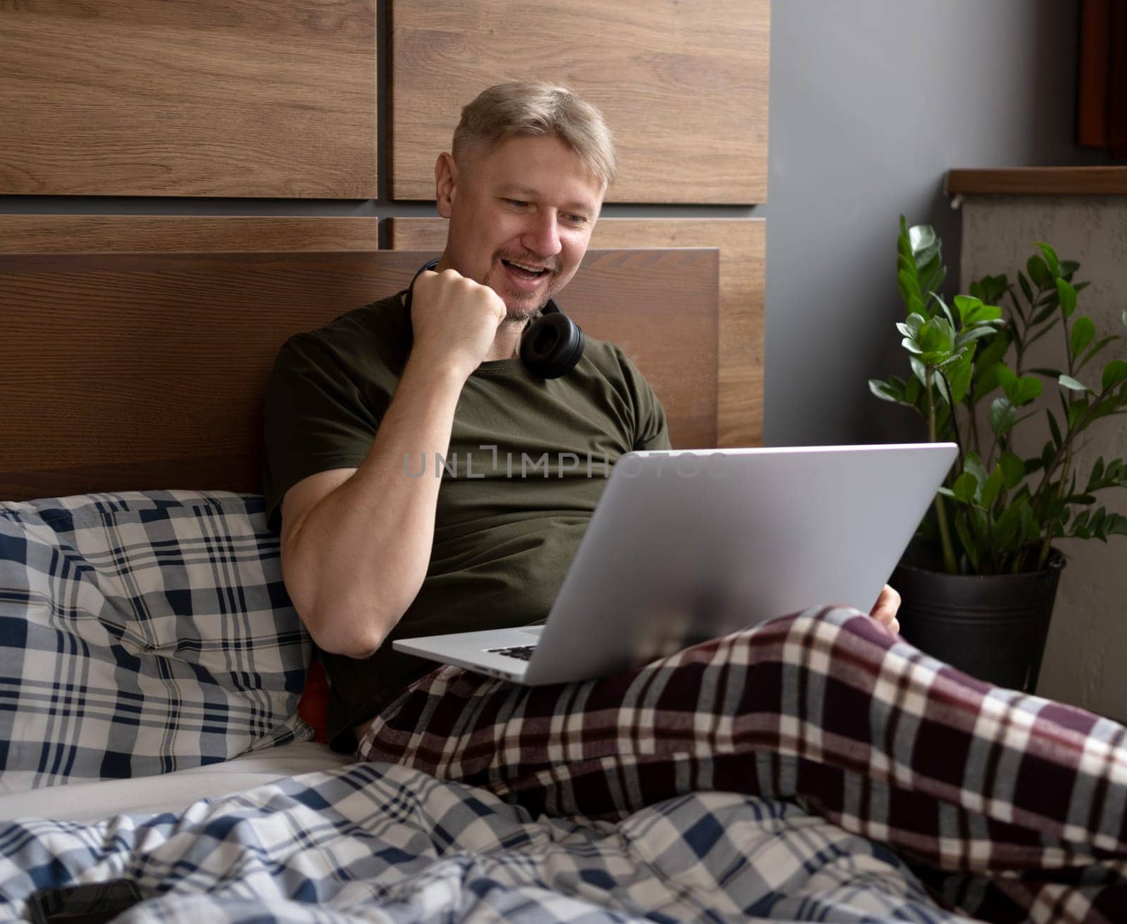 Happy Man Using A Laptop In Bed At Home