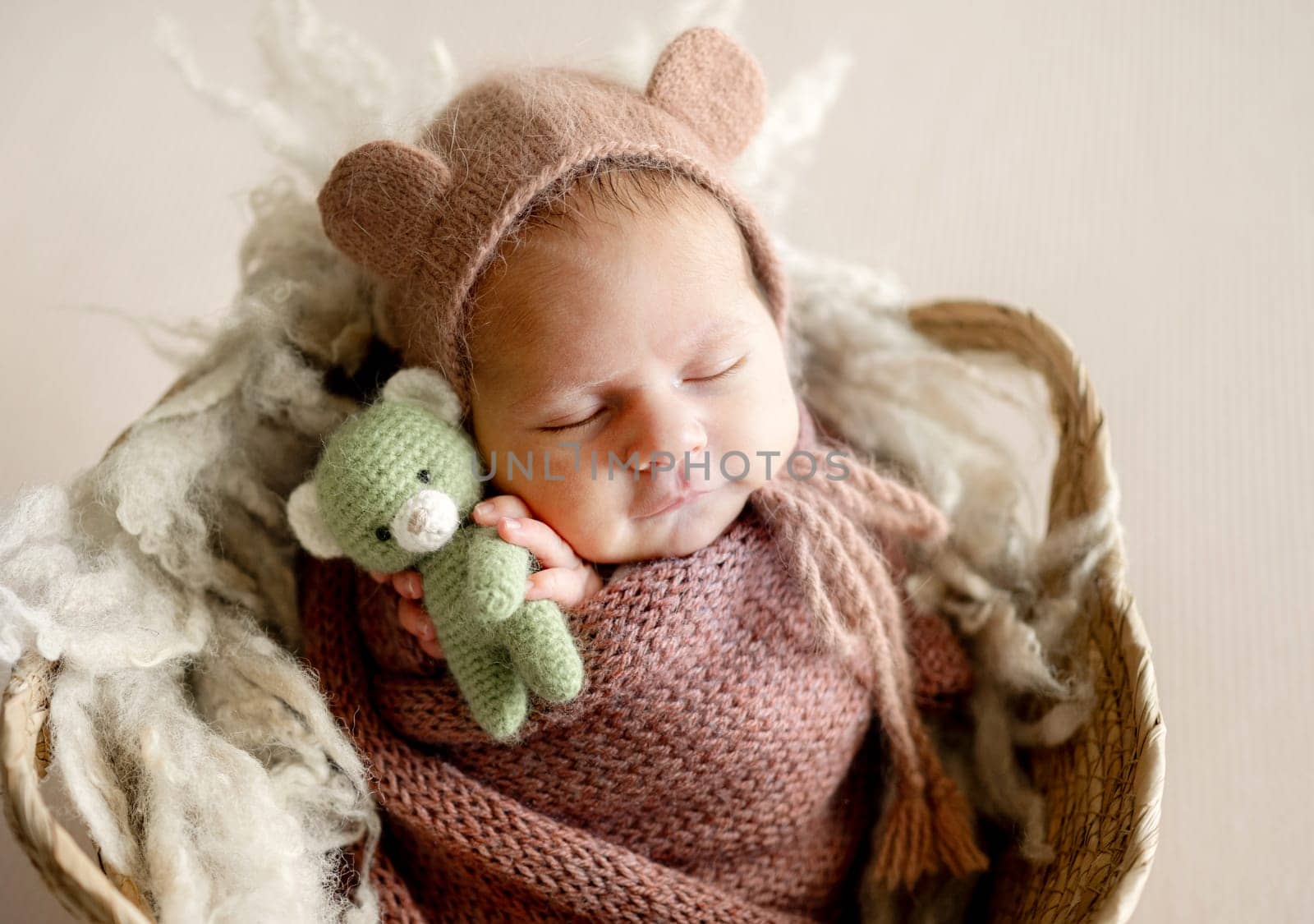 Newborn Baby Sleeping In Fawn's Basket In A Studio Photo