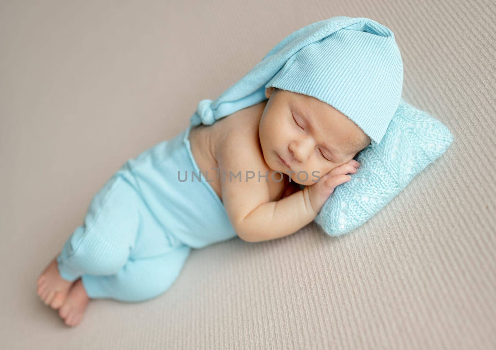Studio Photo Of A Newborn Baby Sleeping In Turquoise Hat And Pants