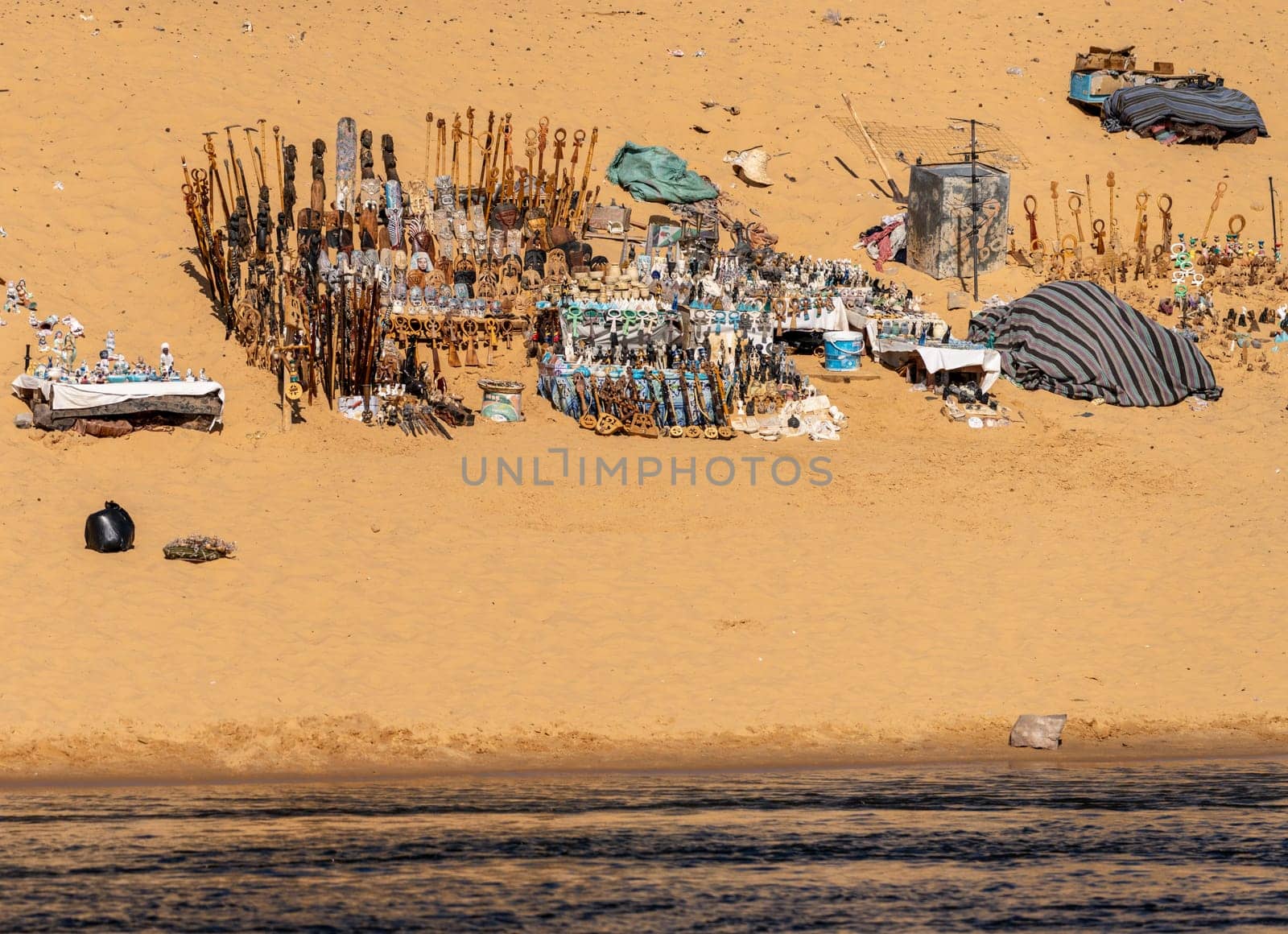 Collection of Egyptian gifts and trinkets on the sandy beach by Nile River in the Nubian village near Aswan