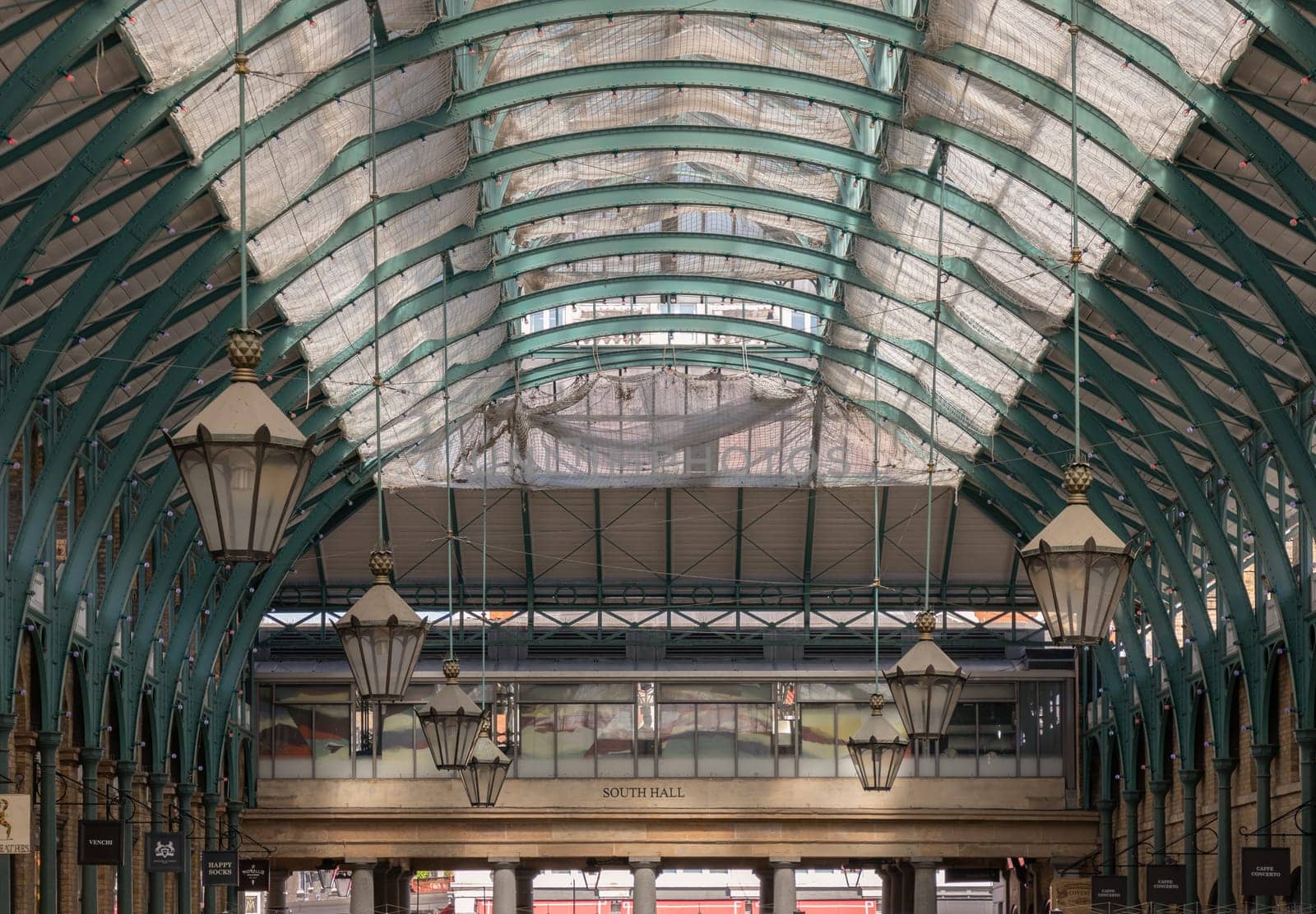 London, UK - May 13, 2025 - Architecture greco-roman style with iron glass roof and Lanterns hanging on the ceiling in Covent Garden Market Hall. View of Metallic framework arch roof with ceiling hanging lamp, use it as your Wallpaper, Poster and Space for text, Selective focus.