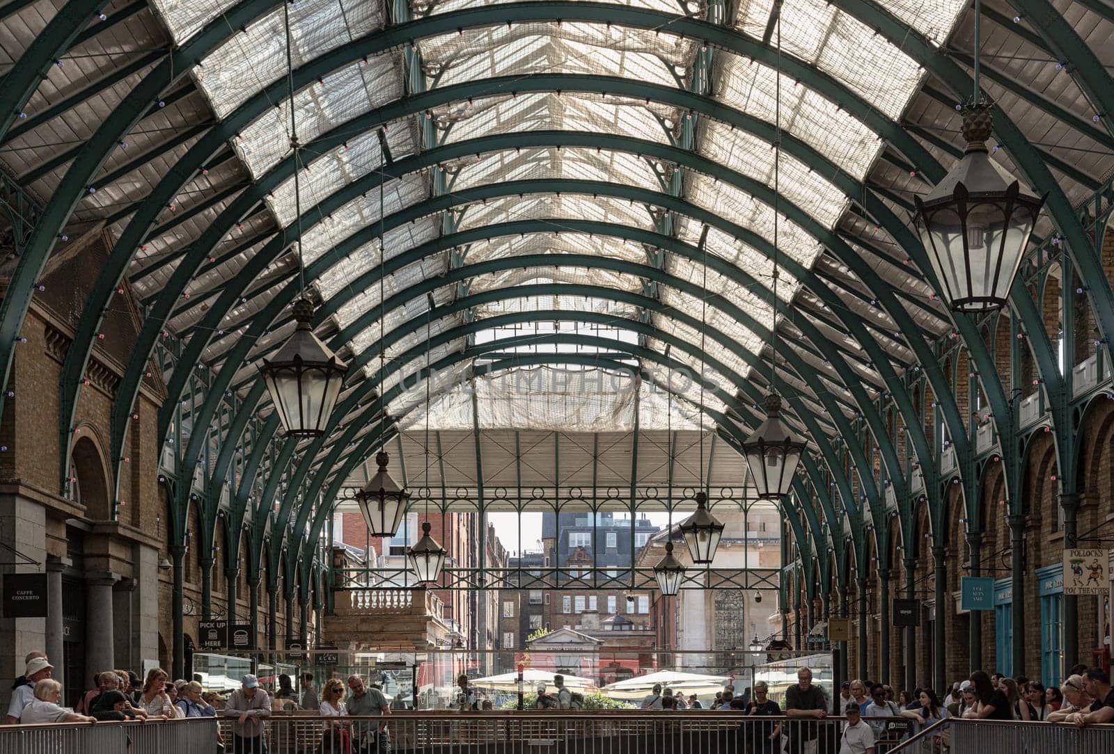 London, UK - May 13, 2025 - The vintage iron glass roof with Lamps on the ceiling of Apple market in Covent Garden Market Hall. View of Metallic framework arch roof with ceiling hanging lamp, use it as your Wallpaper, Poster and Copy space, Selective focus.