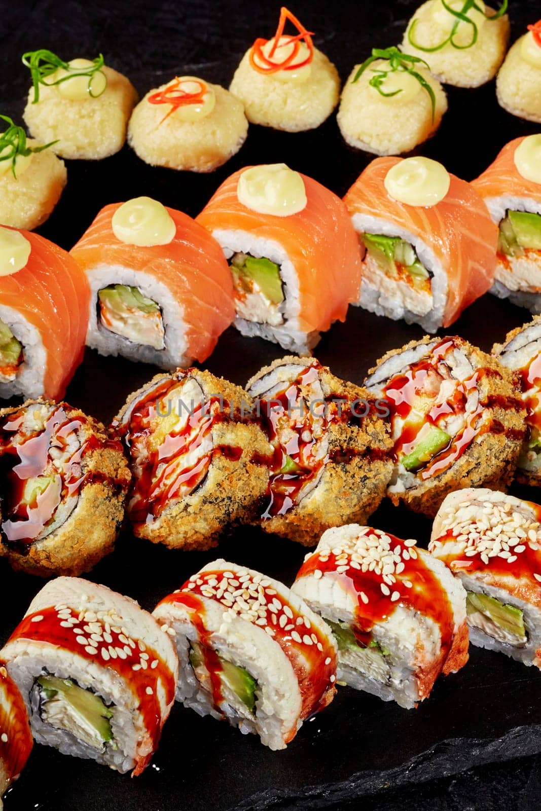Delicious assortment of sushi rolls presented on a black stone surface, showcasing diverse ingredients and culinary techniques