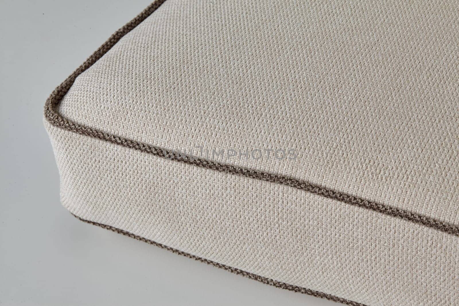 Close-up of beige fabric cushion with brown border detail, showing weaving and texture