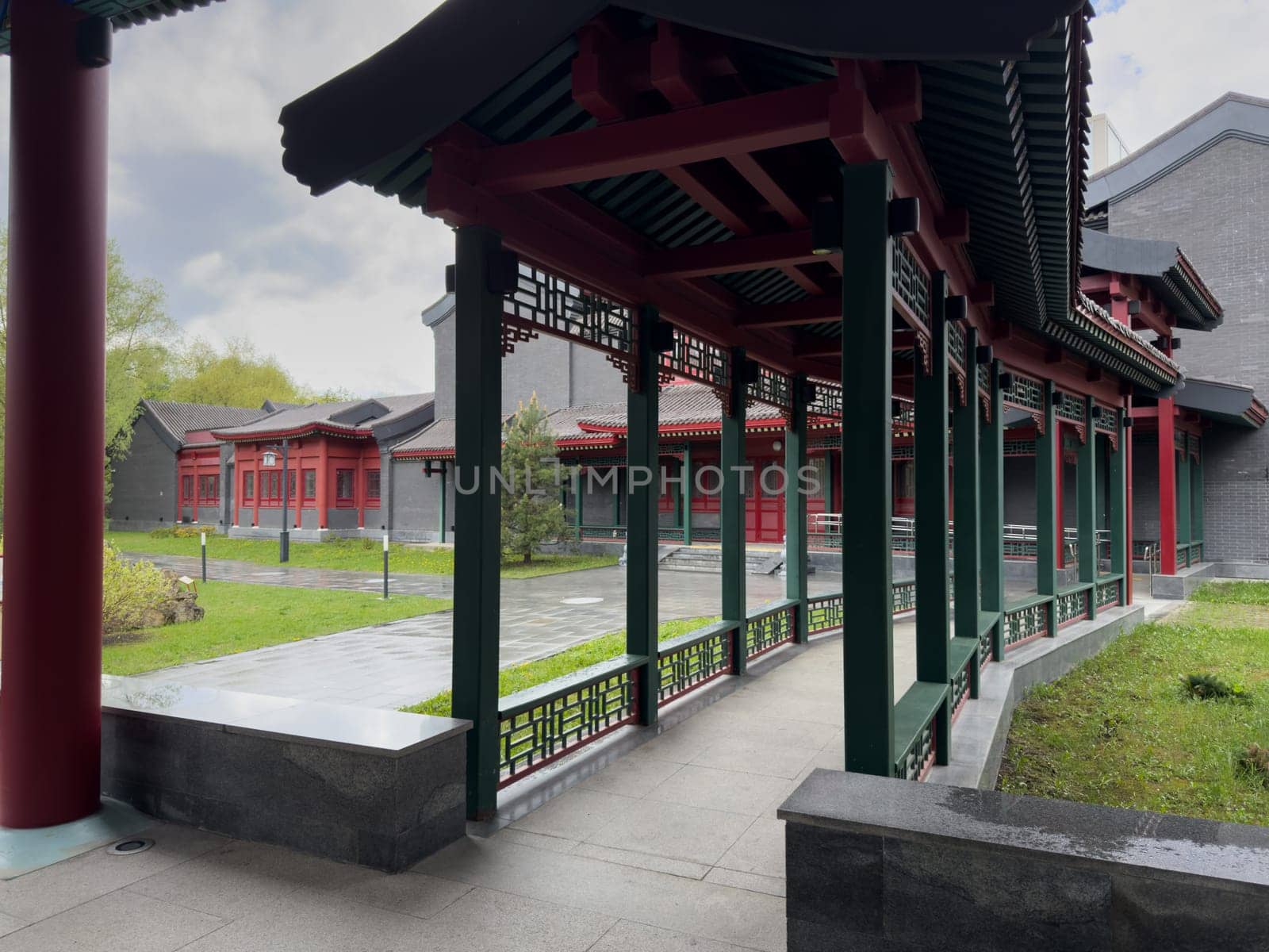 Moscow, Russia, April 25, 2025: Covered gallery in Chinese architectural style with red and green columns, decorative lattice panels and tiled roof, located in public cultural park in Moscow