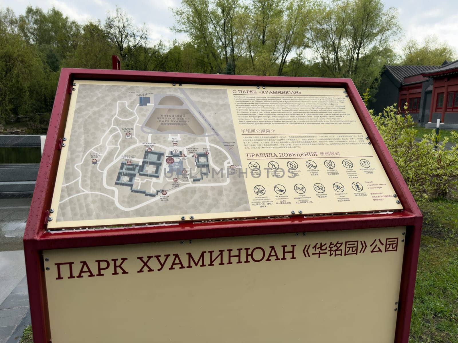Moscow, Russia, April 25, 2025: Close up of bilingual information stand with map and park rules at entrance to Huamin park in Moscow, featuring Chinese cultural motifs and graphic symbols