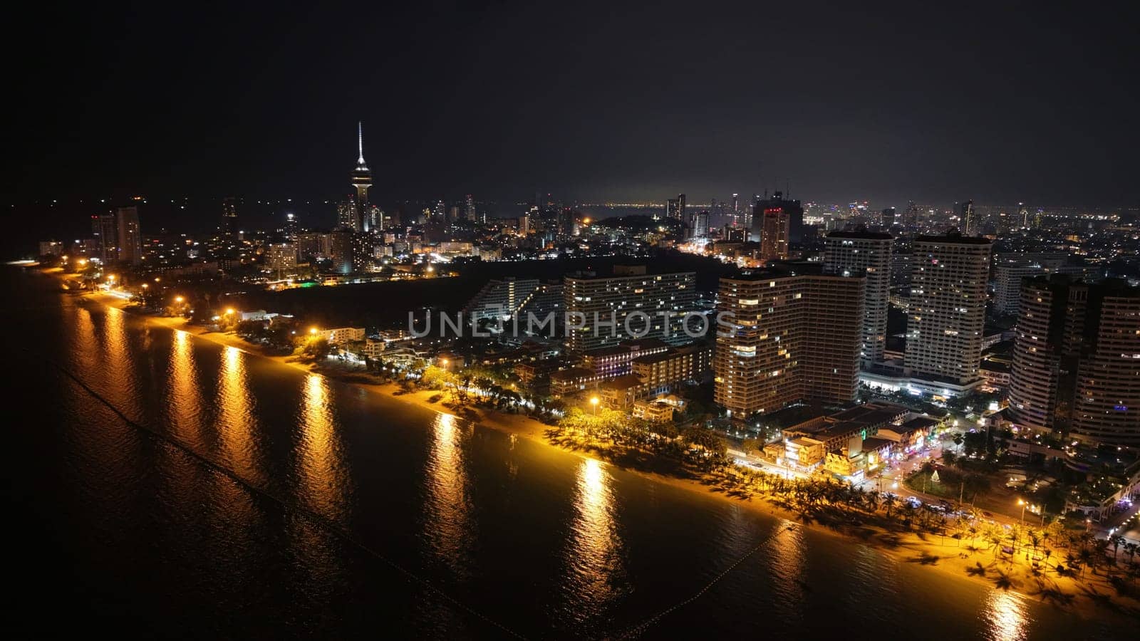 Pattaya cityscape at night showing beachfront hotels, high rise buildings, and the iconic pattaya park tower, illuminating the skyline and coastline with vibrant lights