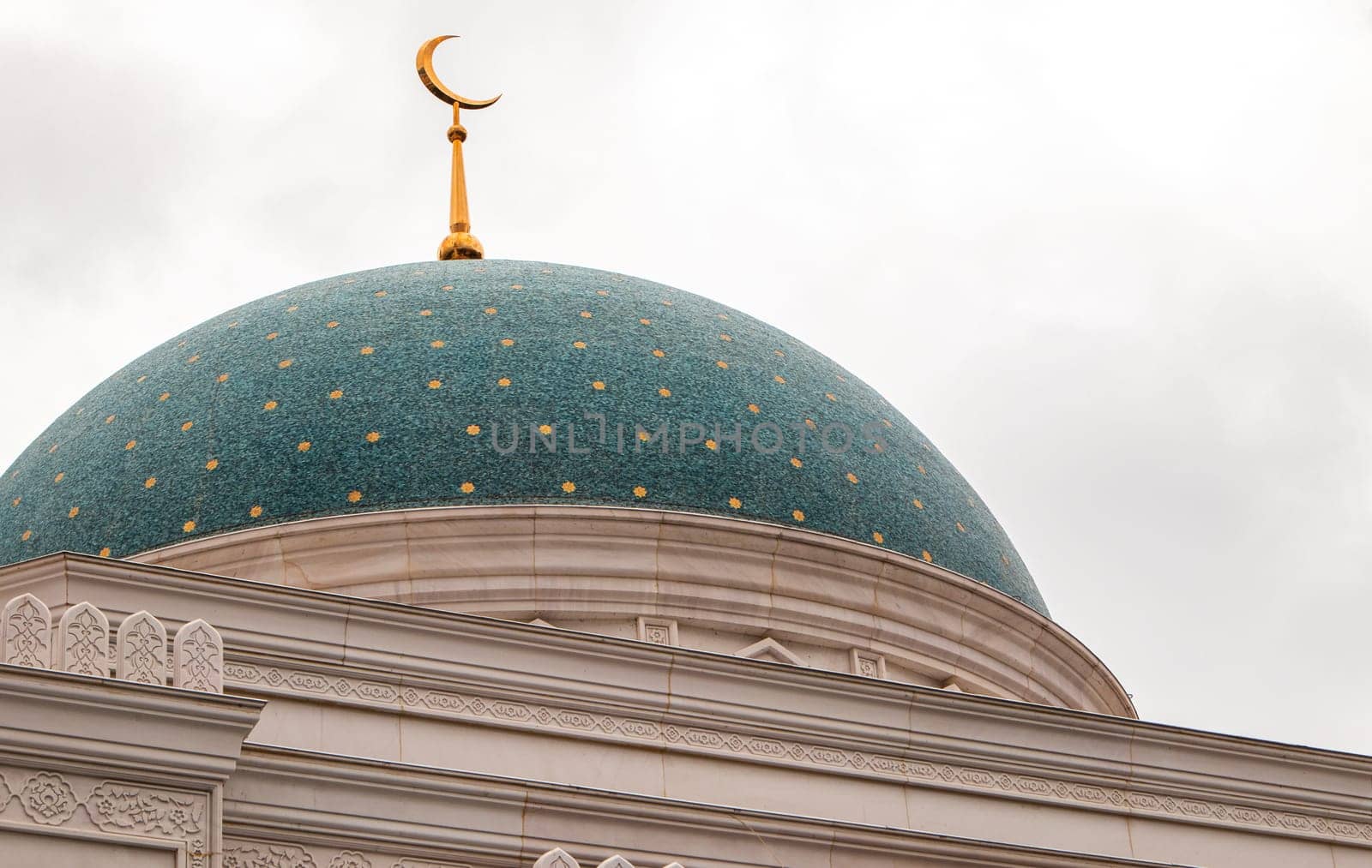 Close-up of the blue dome of the mosque with stars and golden crescent, white stone walls.