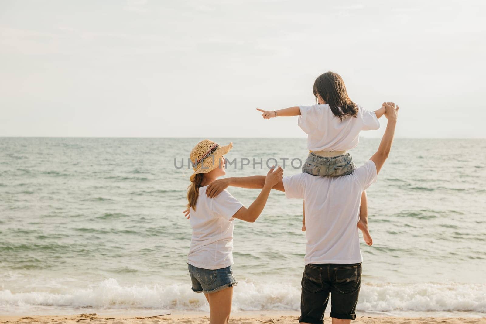Happy family in holiday. Father, Mother and kids having fun together shoulder ride on summer beach, Parents carrying children on neck at beach, family is enjoying their summer time