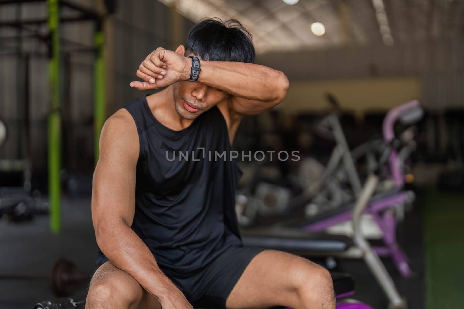 A young man taking a break after a kettlebell workout, reflecting on his fitness journey and commitment to health.