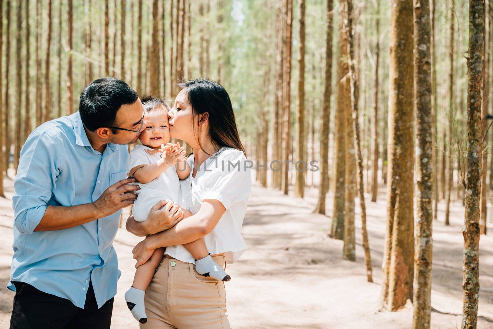 A man and woman holding a baby in a forest