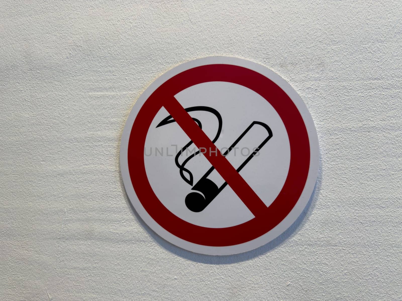 No smoking sign on light textured wall. Classic red prohibition circle with cigarette icon promotes health awareness, indoor safety, and smoke free environment compliance