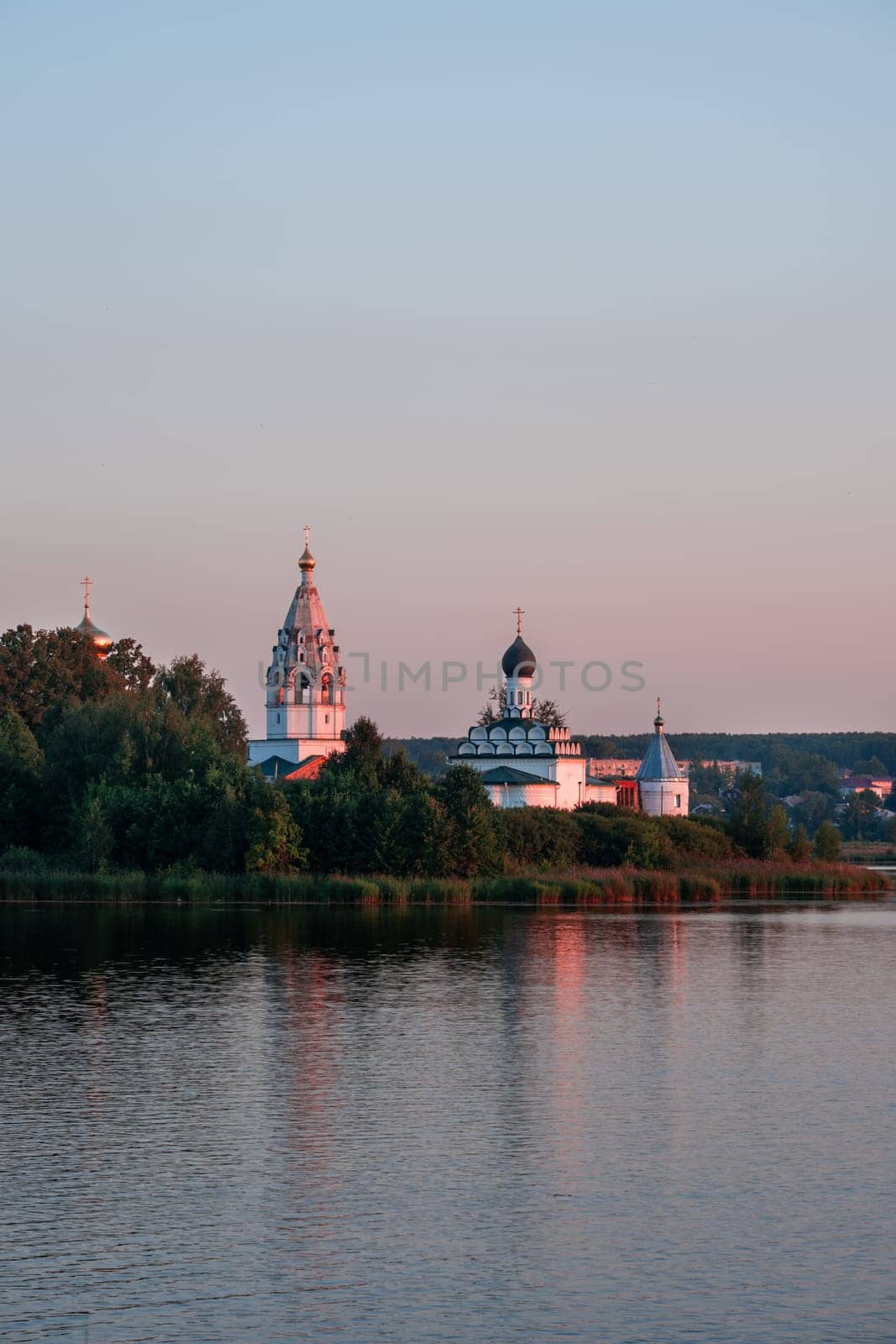 Vorsma, Nizhny Novgorod Region, Russia - 06.08.23. The historic Holy Trinity Ostrovoezersky Monastery is reflected in the waters of Lake Tuskanka at sunset.