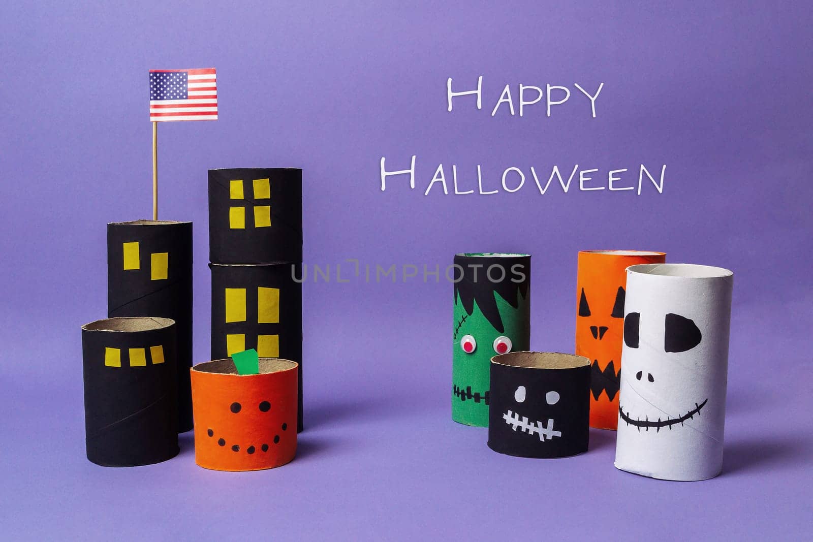 Sign that says Happy Halloween. There are several paper tubes with faces on them. One of the tubes has a flag on top