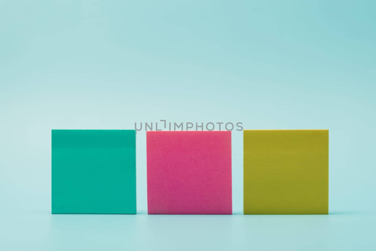 Colorful Post-it notes arranged on blue background. Concept of reminders, brainstorming, organization, productivity, office work, and creative planning.