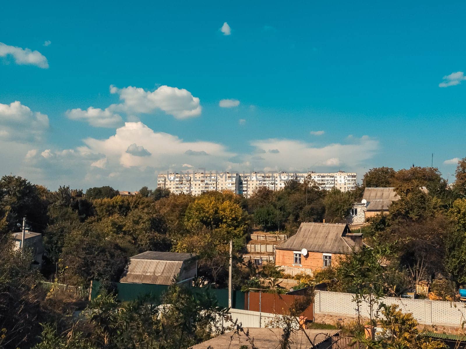Small town with a few houses and a large building. The sky is blue and there are some clouds