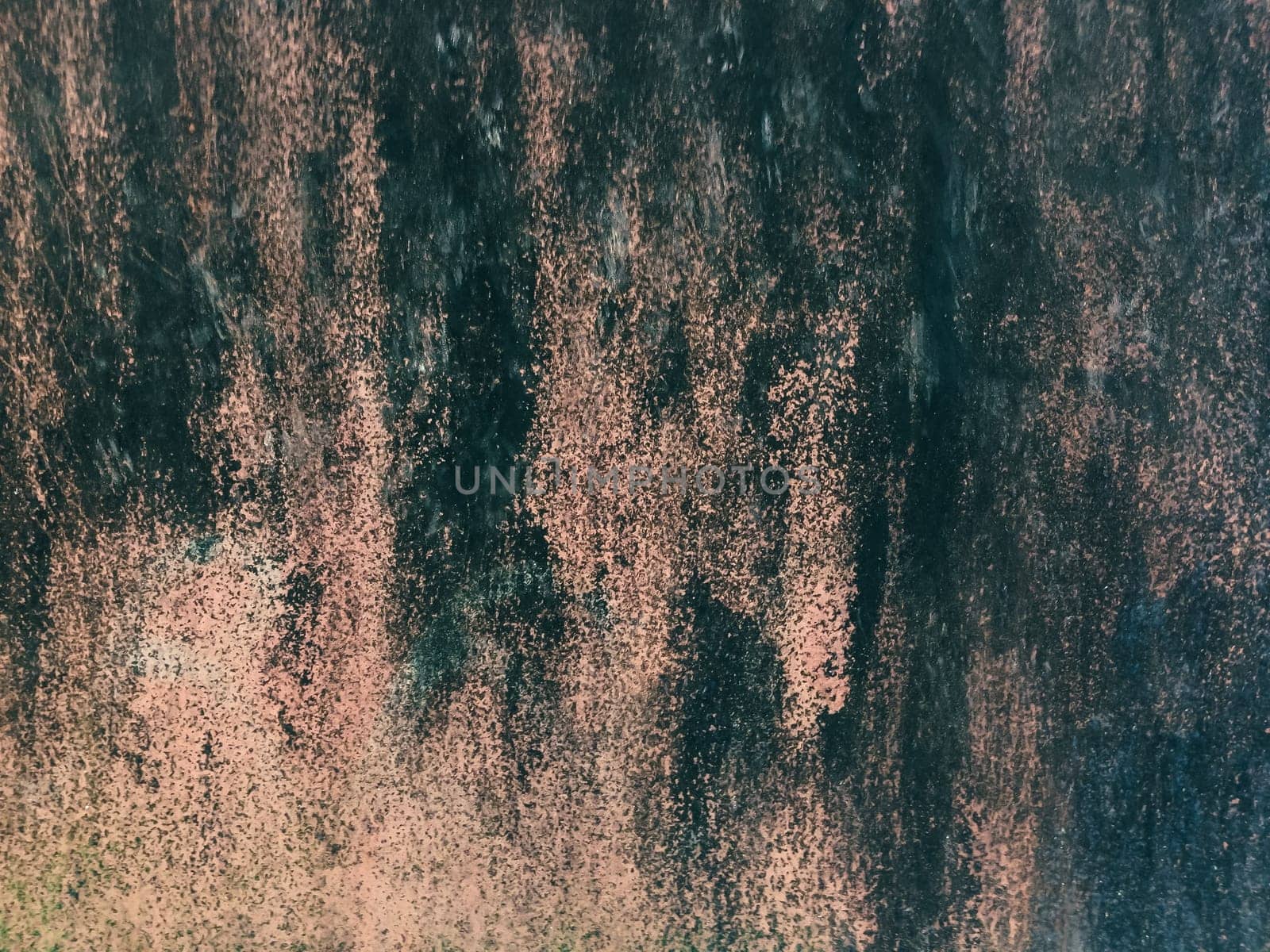 Wall with a black and brown texture. The wall has a few spots of pink. The wall is covered in paint