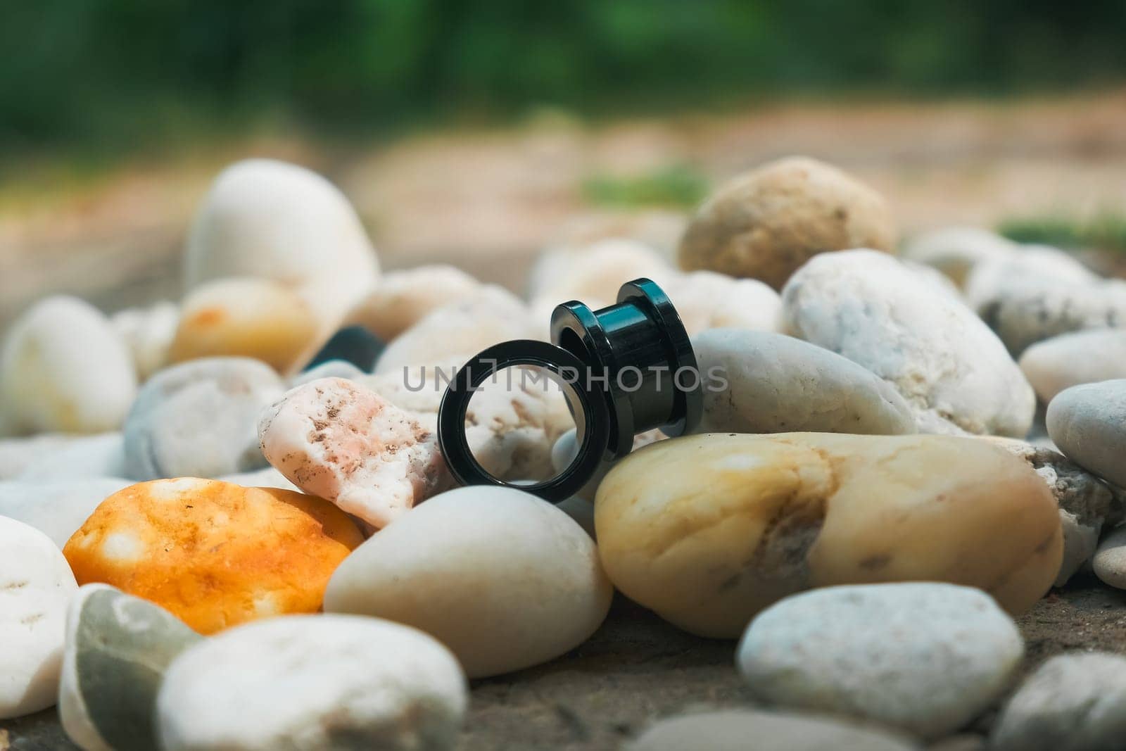 Two black ear plugs are on top of a pile of rocks. The rocks are white and grey