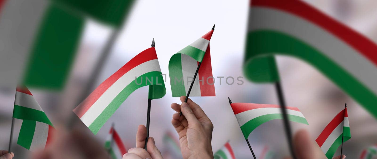 Hungary flags in their hands on a blurred urban background. The photo illustration was created without the use of artificial intelligence, only using Photoshop.