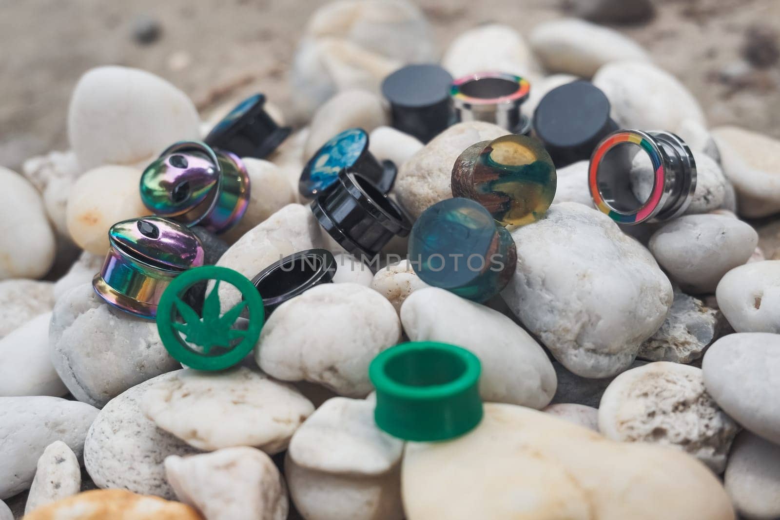 Pile of earrings with one that says "weed" on it. There are many different colors and designs