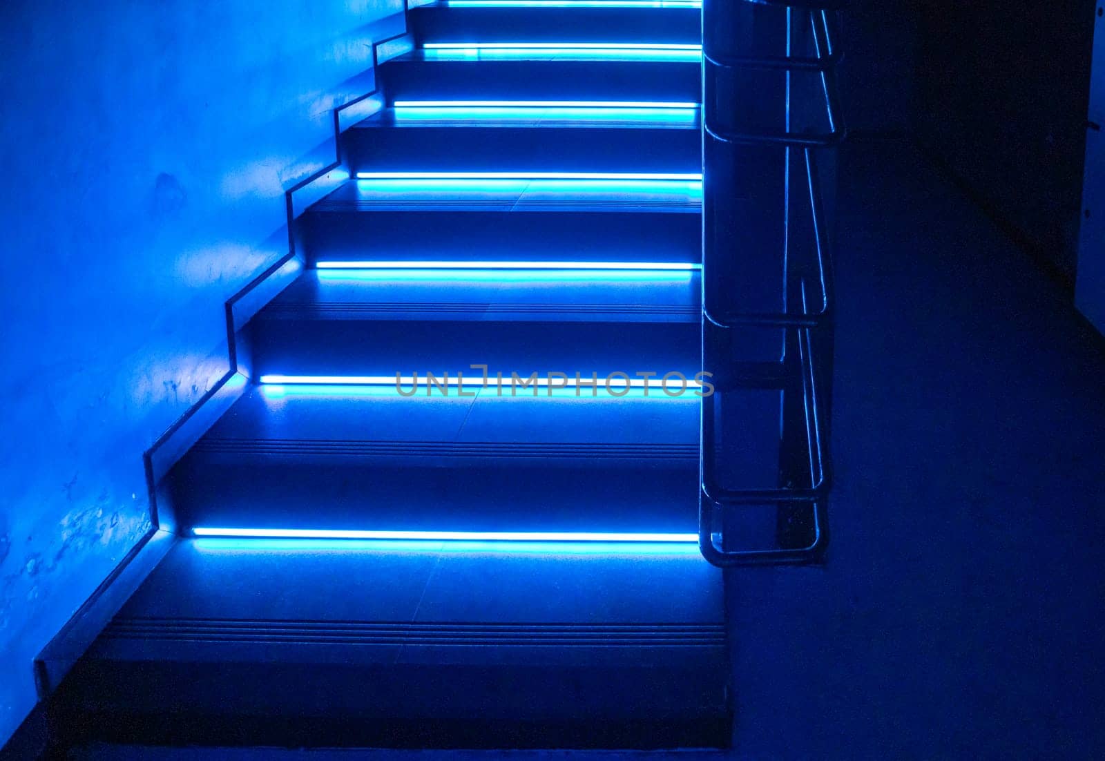 Abstract background with dark floor and blue neon light, empty scene for presentation or show of products. Glowing lights in the shape of a staircase.