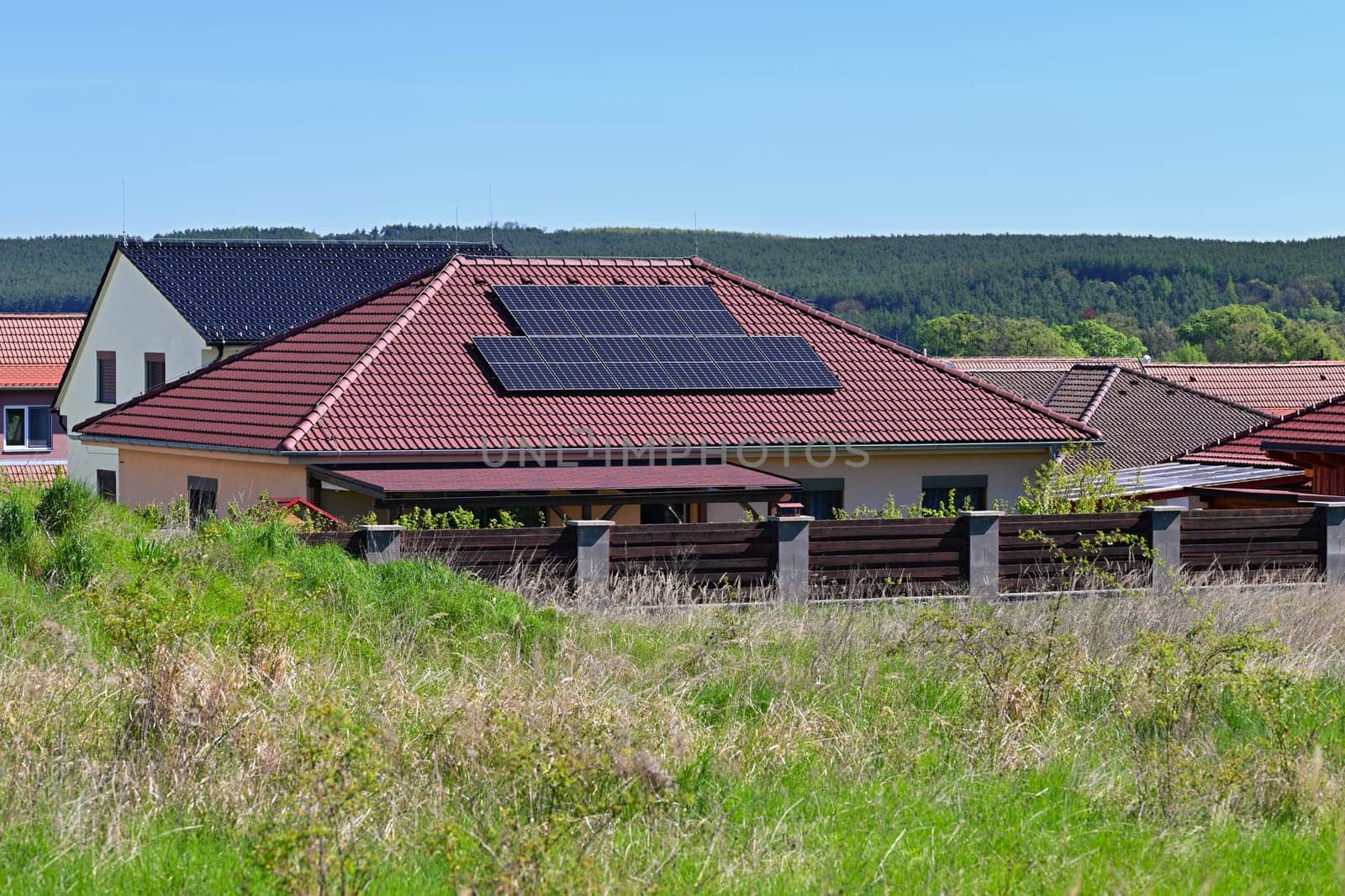 Family house with solar panels on the roof. Home photovoltaic power plant. Concept for industry and green cheaper electricity from renewable sources.