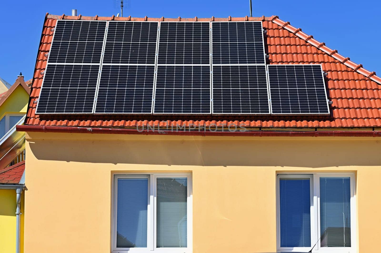 Family house with solar panels on the roof. Home photovoltaic power plant. Concept for industry and green cheaper electricity from renewable sources.