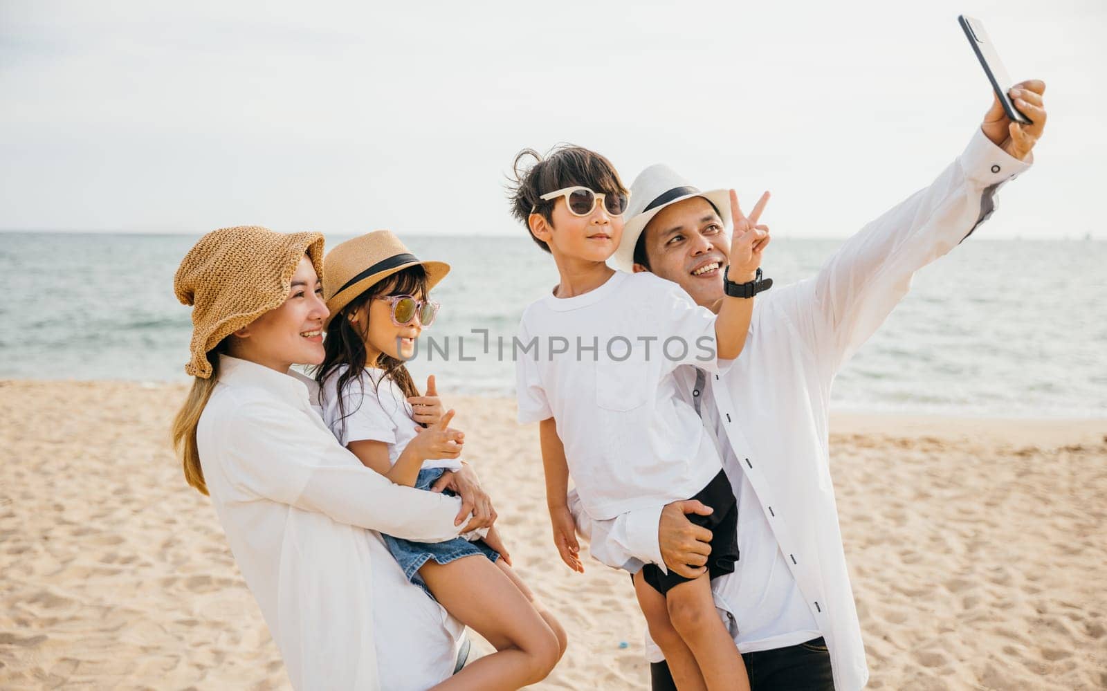 Beachside happiness captured in a family selfie near the sea. Smiles laughter and the joy of togetherness make this moment unforgettable during their summer travel. Family on beach vacation