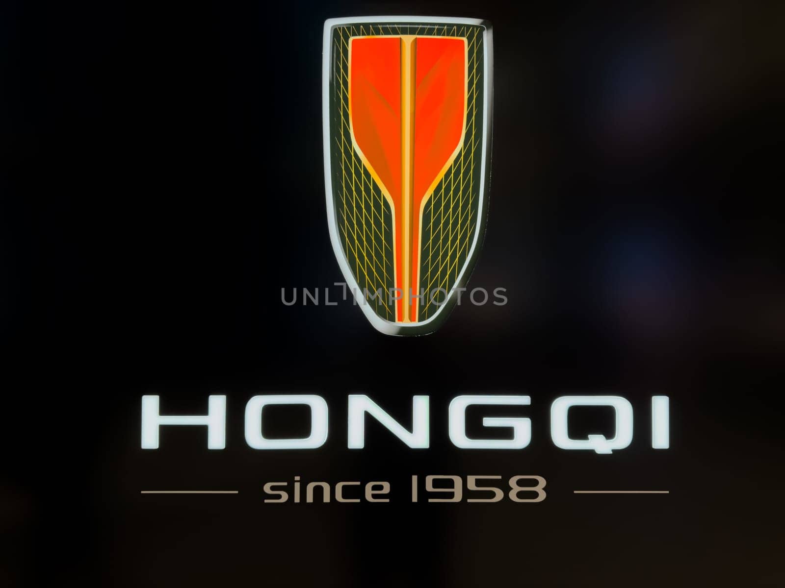 Moscow, Russia, April 25, 2025: Close up view of illuminated Hongqi logo with brand slogan since 1958 on dark background, showcasing the identity of the Chinese luxury car manufacturer