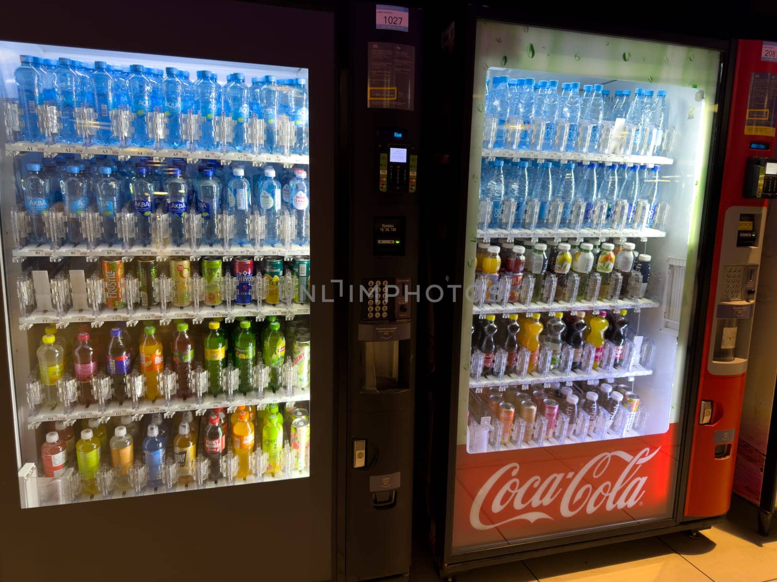 Moscow, Russia, April 25, 2025: Illuminated vending machines offering wide range of bottled drinks including water, juice, tea and soda, with Coca Cola branding in shopping mall setting
