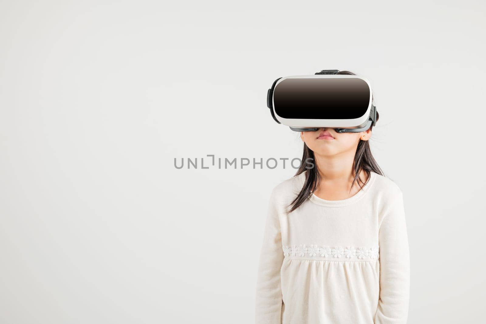 Smiling young kid girl confidence excited wear VR headset device during virtual reality experience isolated white background, Asian happy portrait kindergarten child playing video game studio shot