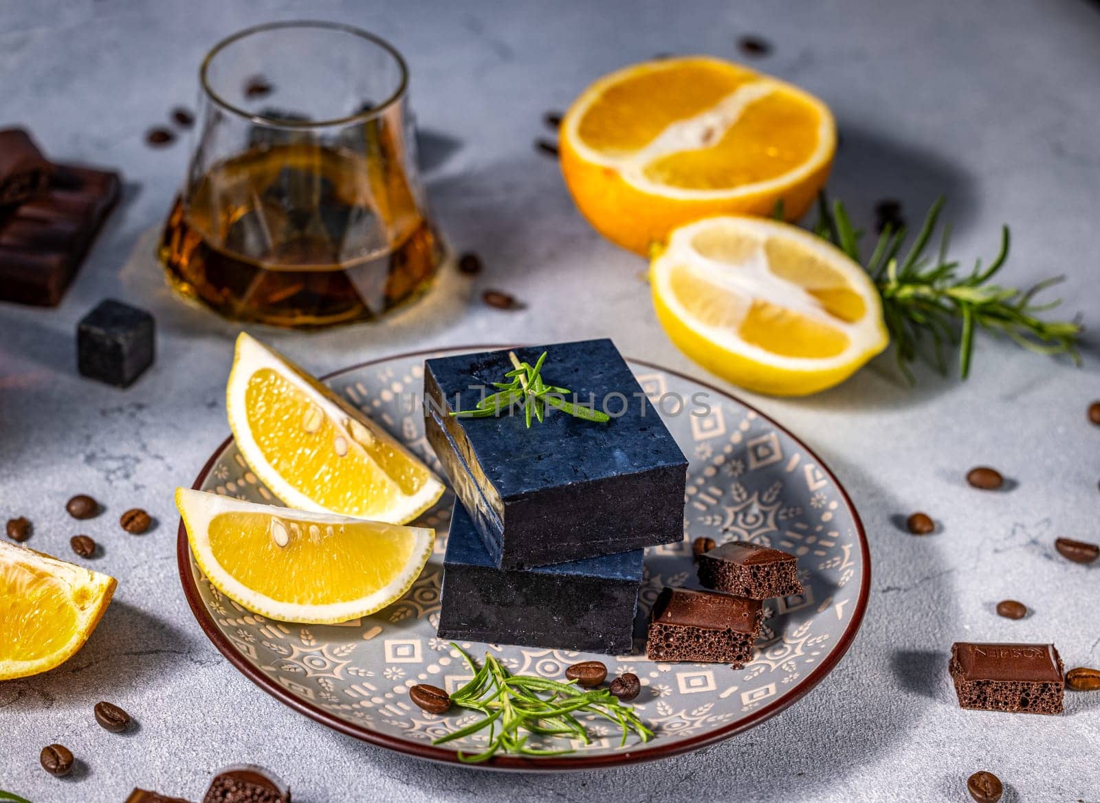 Composition featuring Gourmet black cheese served with lemon, rosemary, coffee beans, aerated chocolate and glass of whisky