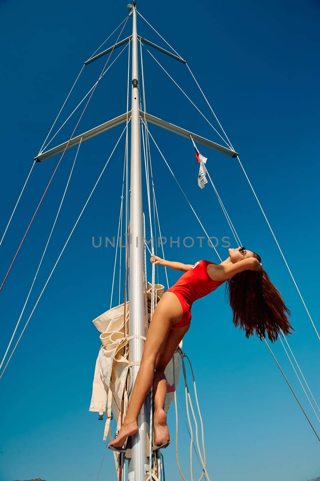 Turkey, Marmaris, 05 October 2021: A beautiful girl in a red swimsuit poses on the mast of a sailing boat, a sexy figure, sunny day. High quality photo