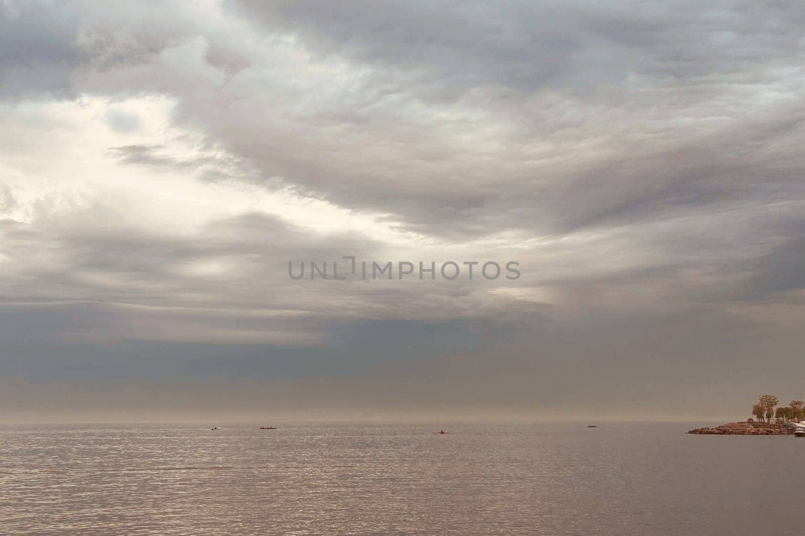 Sunrise and dramatic clouds. Early morning serene seascape in spring. Serene Spring Dawn.Witness the tranquil beauty of an early spring morning. The sun rises, casting a warm glow upon a calm sea, while dramatic clouds paint the sky, creating a breathtaking and serene seascape.