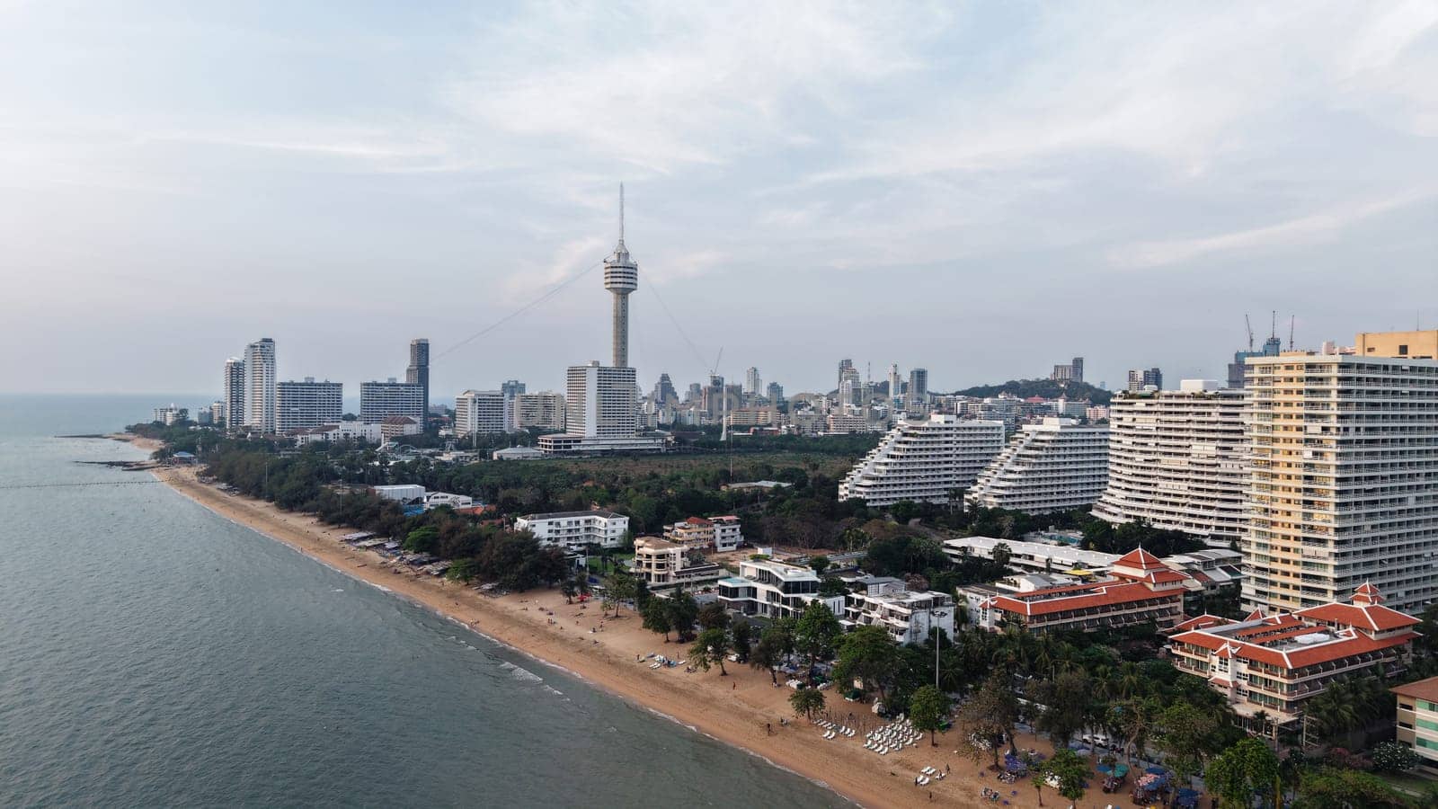 Tourists enjoying pattaya beach at dusk with the city skyline dominating the coastline, offering a stunning view of the vibrant cityscape meeting the tranquil sea