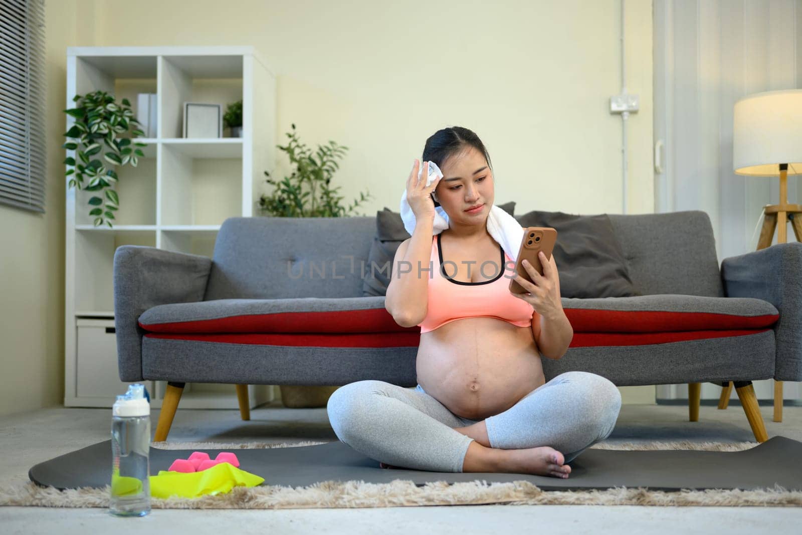 Pregnant woman in activewear takes a break from her workout.