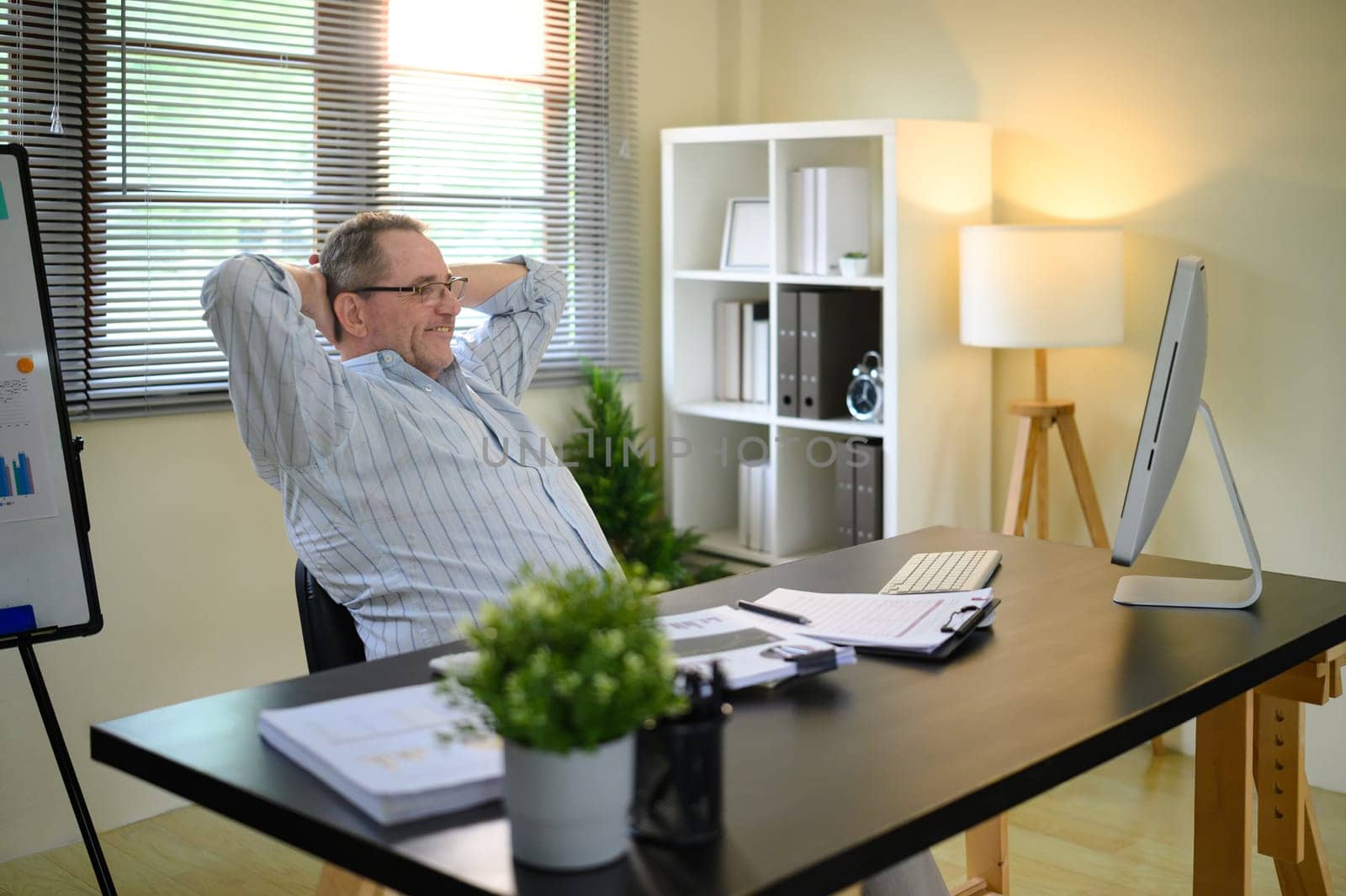 Senior man relaxing after completing tasks in a modern workspace.