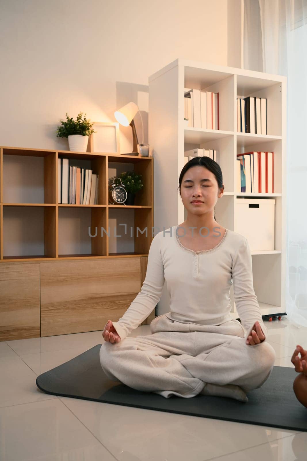 Teenage asian girl meditating in a calm and cozy home environment.