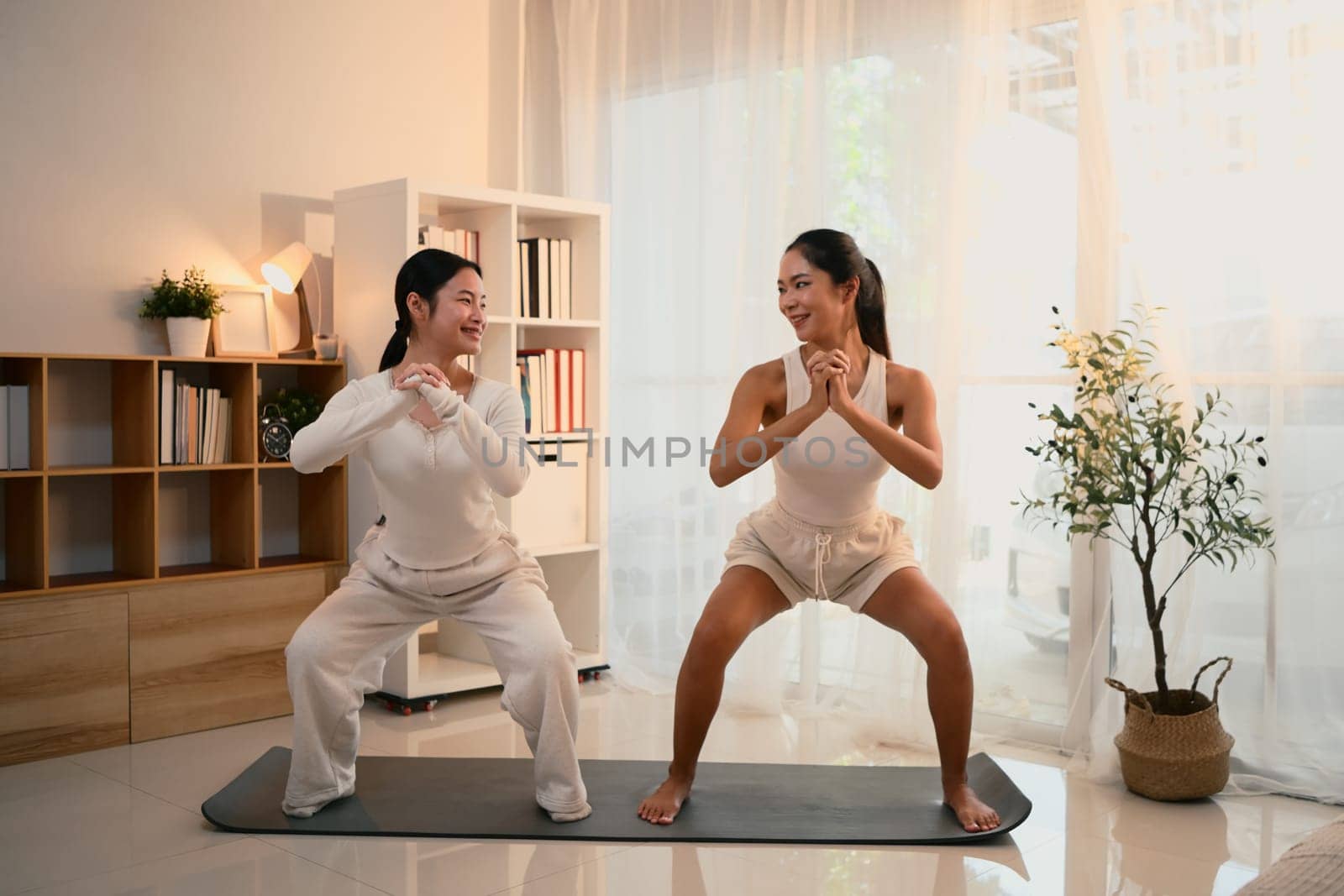 Asian mom and her teen daughter doing yoga workout at home.