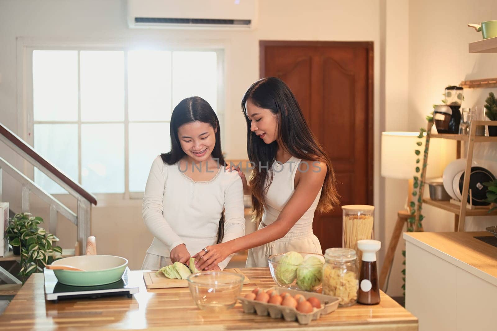 Mother and teenage daughter preparing a healthy meal together in a warm kitchen.