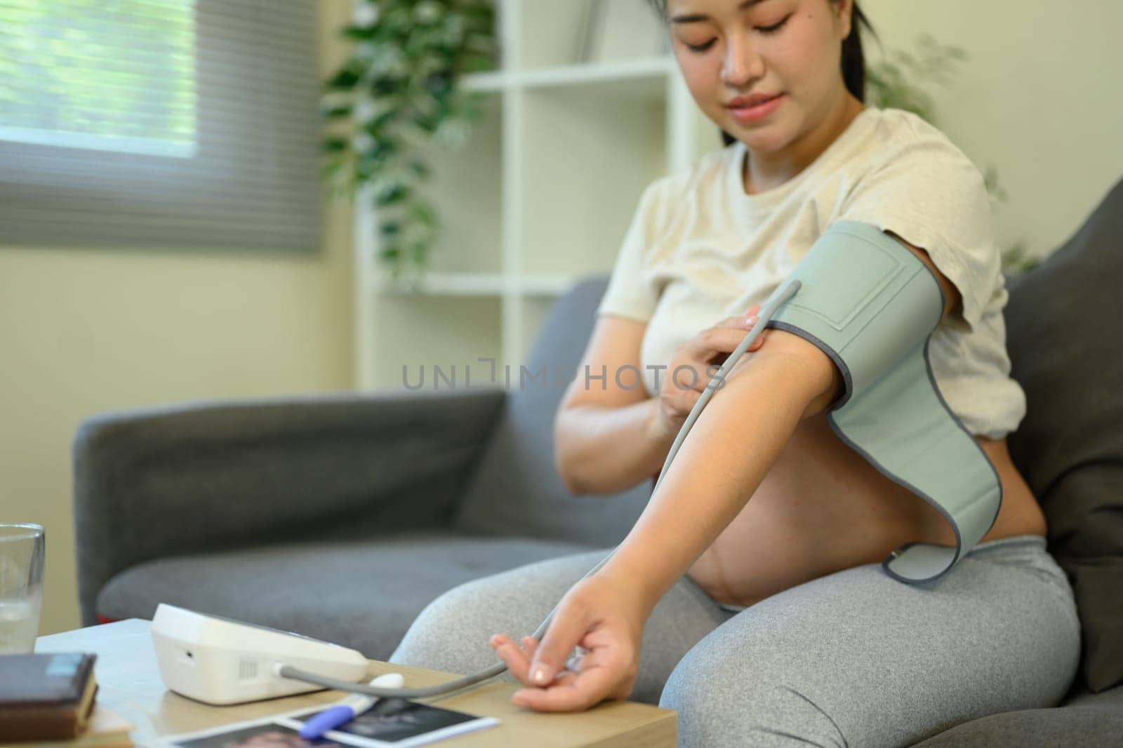 Pregnant woman checks her blood pressure at home. Maternal wellness and health care concept.