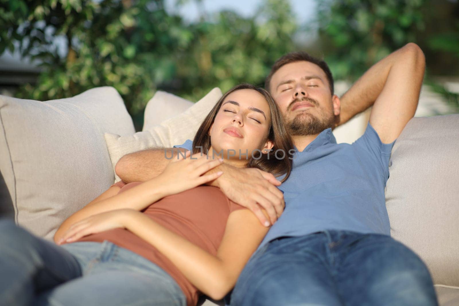 Couple relaxing sleeping together lying on a couch in a garden