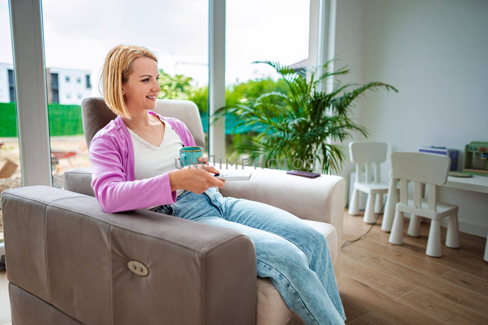 Woman enjoys quiet time with a cup in bright room.