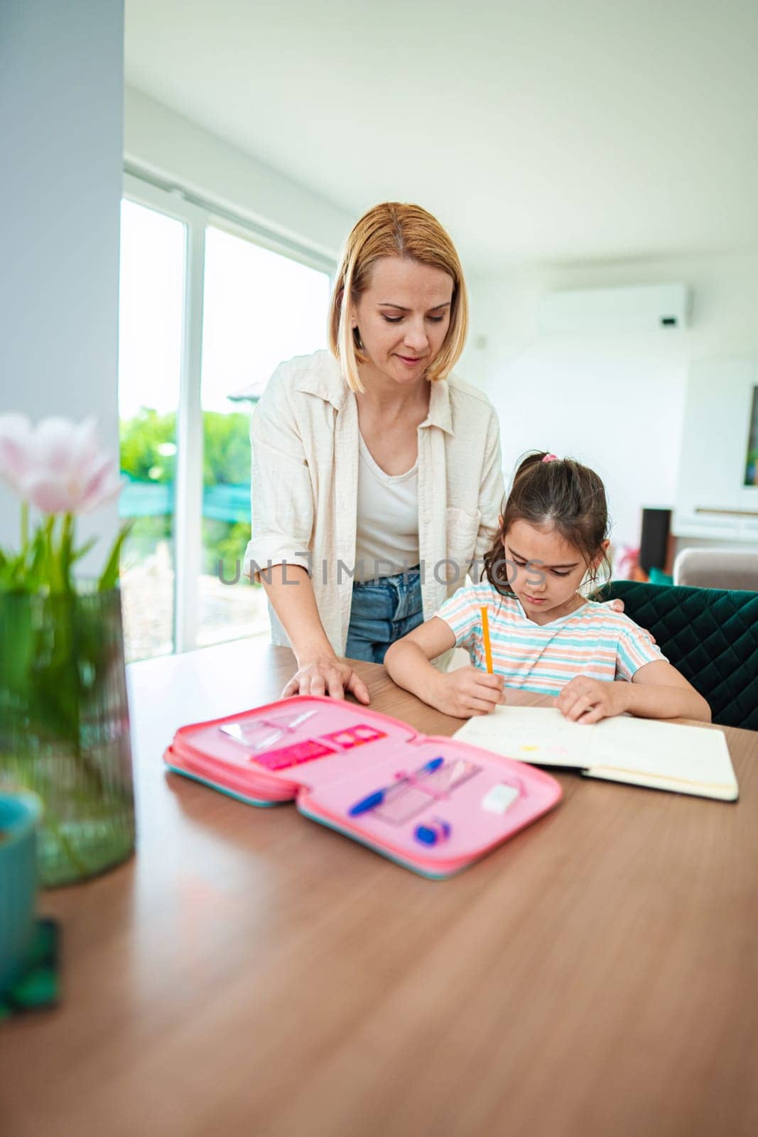 Caring guidance during homework time in a bright room.