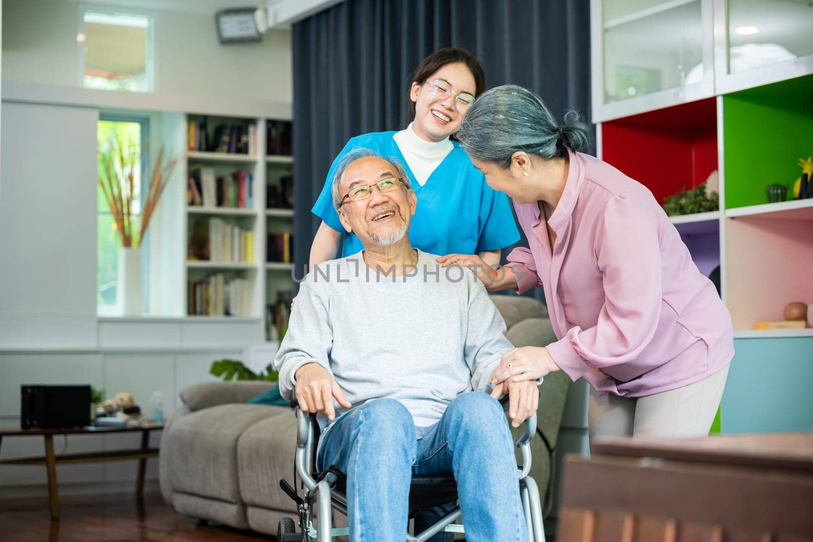 Asian old man on wheelchair with couple and nurse relaxing walking at home, healthcare medical service at nursing home, Happy nurse and wife support retirement senior elderly man