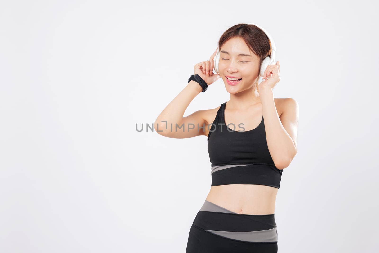 Dance becomes natural when this slim woman wears wireless headphones. A cheerful workout turns into a fun session as she lets herself dance to the rhythm of the music. isolated studio white background